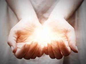 Cupped hands held together and holding a luminous ball of light
