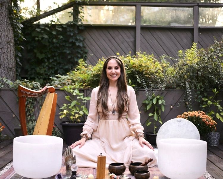 Kimberly smiling and sitting with sound healing instruments
